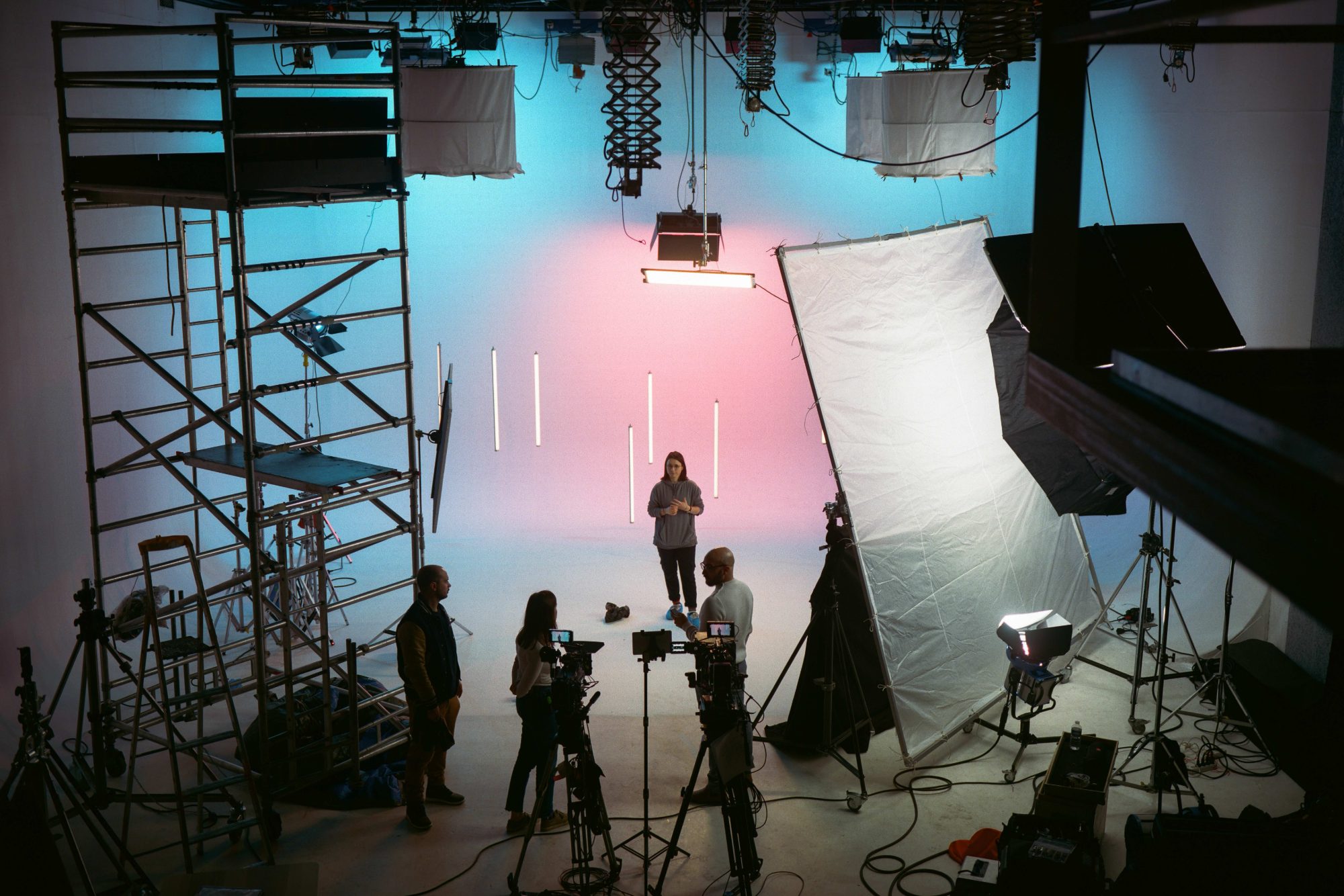 A film stage in use: cyclorama lit blue and pink, cameras and crew