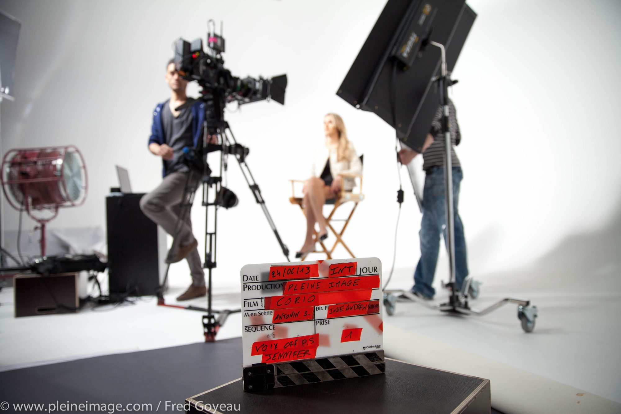 Pleine Image clapperboard in front of the crew, camera and speaker, on white